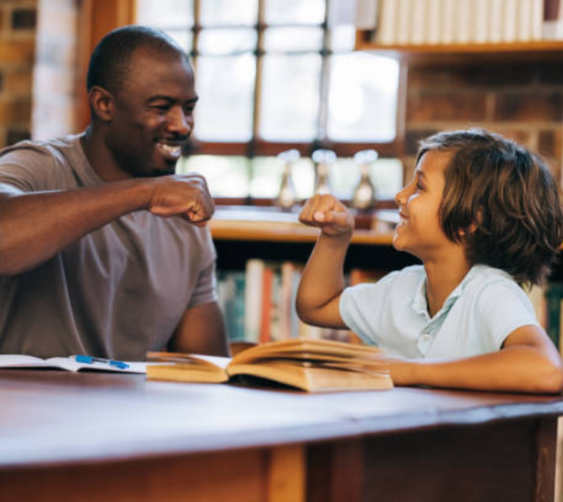 A man and boy sitting at table with books.