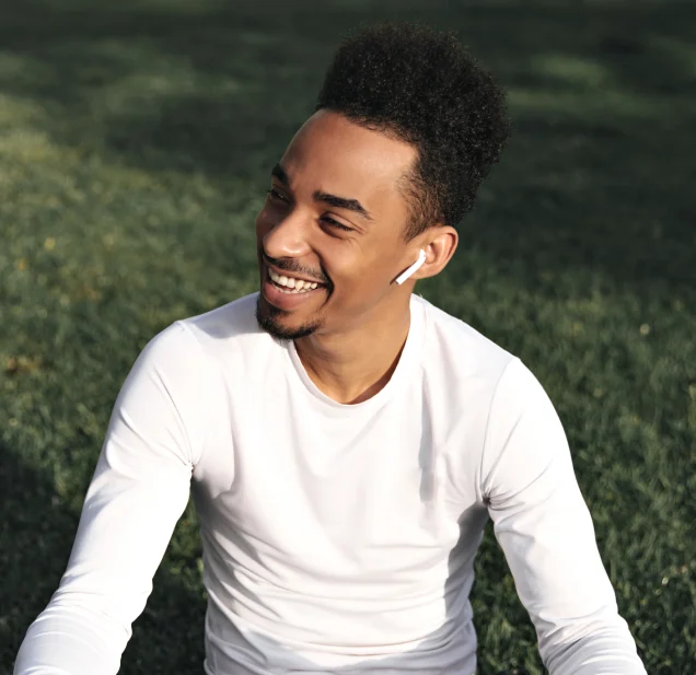 A man sitting on the grass with his ear buds in his ears.