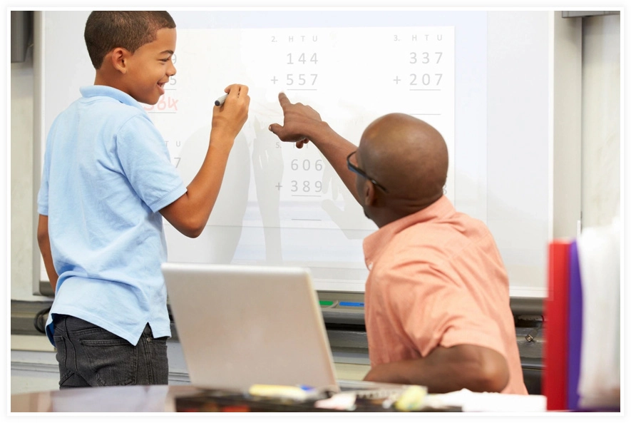 A man and boy are pointing at something on the whiteboard.